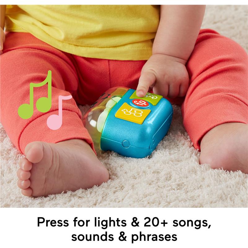Fisher Price Laugh & Learn Play Along Ear Buds toy with colorful buttons, pressed by a toddler, on a soft surface.
