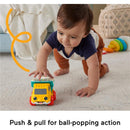 Toddler playing with a Fisher Price Poppity Pop Dump Truck toy, pushing it to activate ball-popping action.