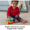 A toddler in a red shirt plays with a colorful Fisher Price Poppity Pop Dump Truck toy, engaging with its bright colors and sounds.
