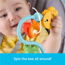 Baby playing with a colorful spinning toy attached to a high chair, featuring a bee and fruits, encouraging sensory exploration.