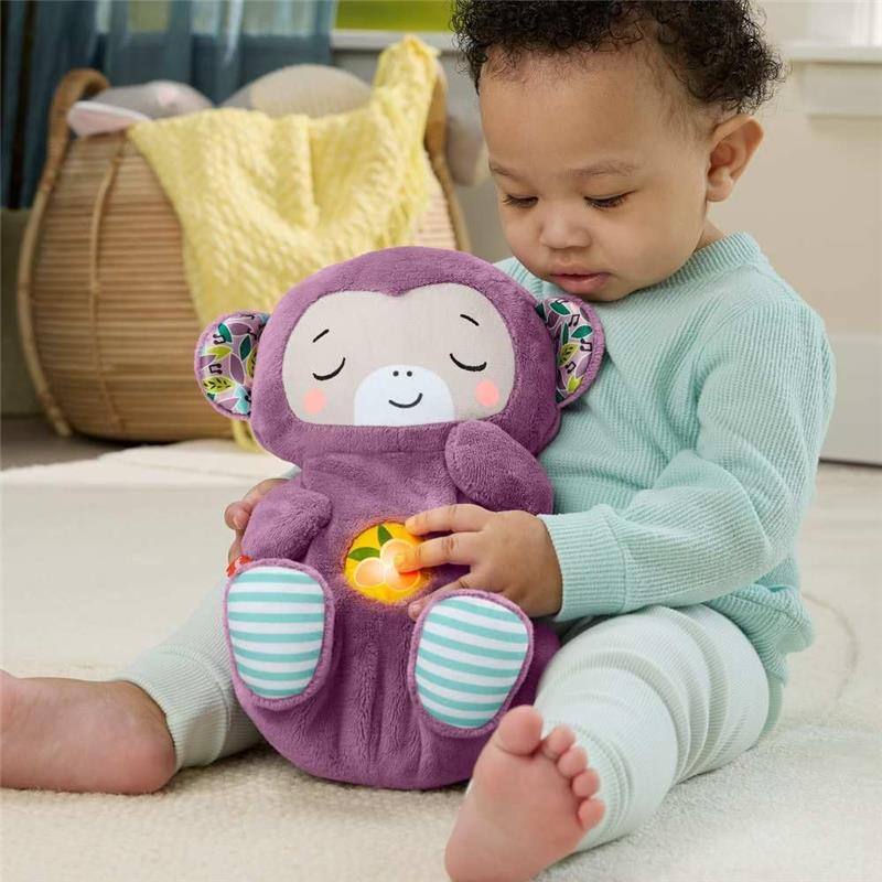 Toddler sitting on the floor, hugging a purple plush monkey sound machine that glows softly while displaying a cheerful expression.