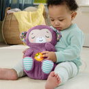 Toddler sitting on the floor, hugging a purple plush monkey sound machine that glows softly while displaying a cheerful expression.
