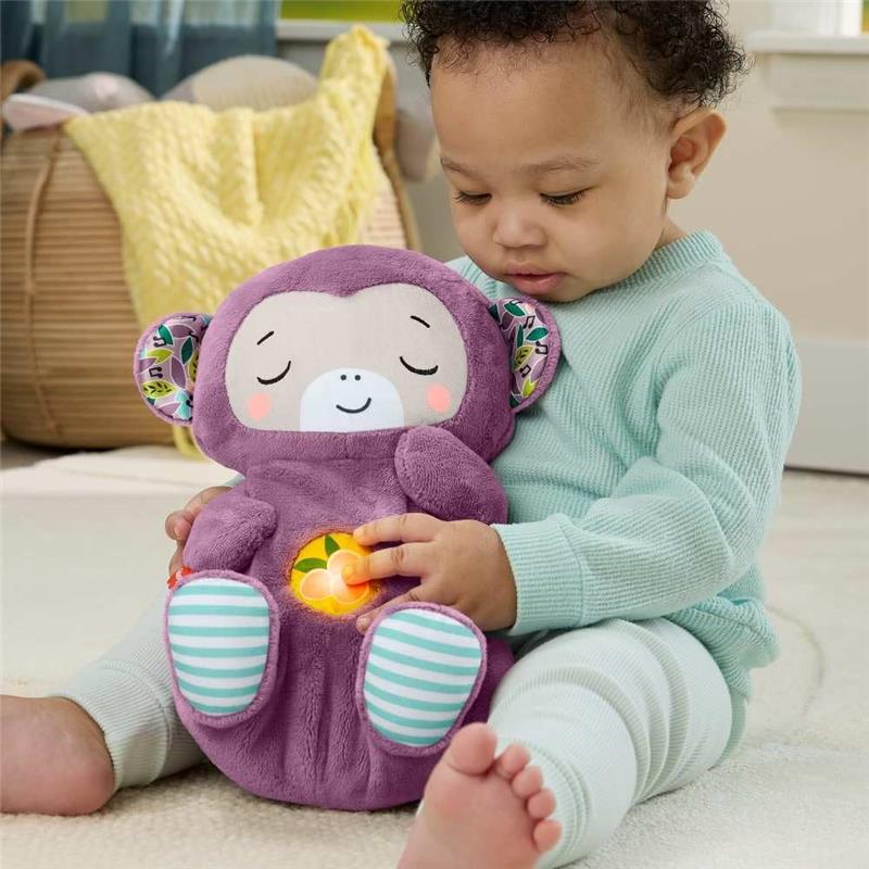 Toddler interacts with a purple monkey plush sound machine, featuring a light-up button, in a cozy indoor setting.