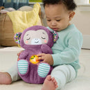 Toddler interacts with a purple monkey plush sound machine, featuring a light-up button, in a cozy indoor setting.