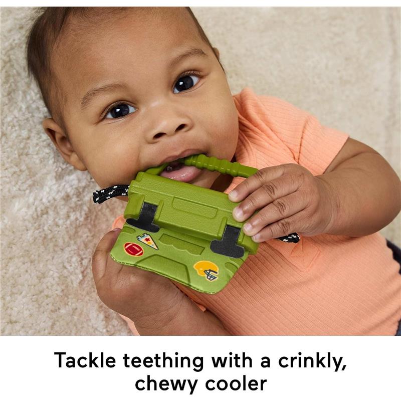 Infant bites a green, crinkly cooler toy with sports stickers, promoting teething relief and sensory play.