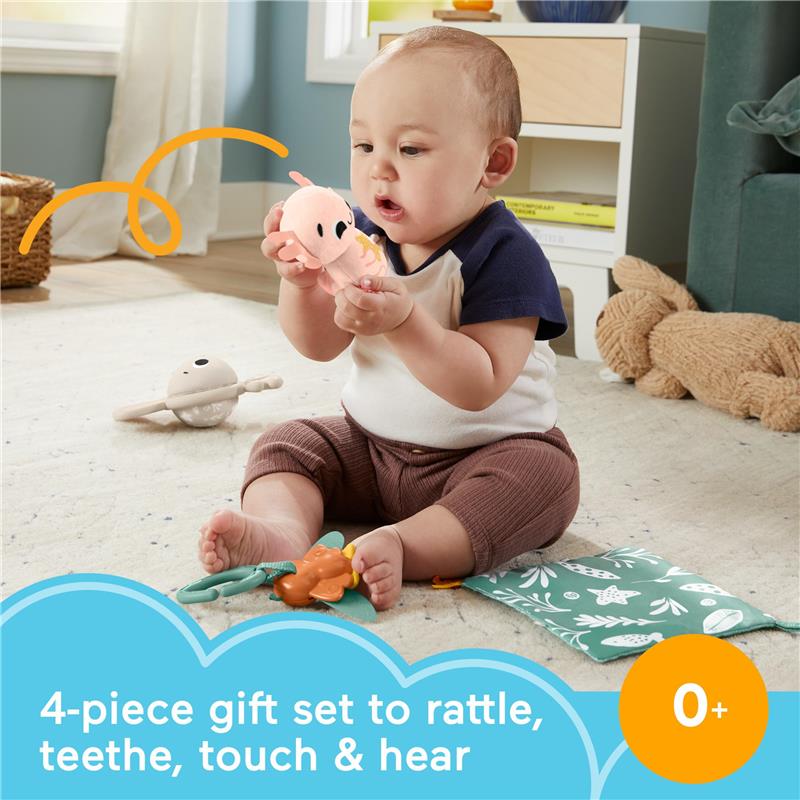 Baby sits on a soft rug holding a pink toy while surrounded by a 4-piece sensory toy set, designed for rattling, teething, and tactile exploration.
