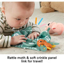 Baby exploring the Fisher Price So Many Senses Set, featuring a rattling moth and crinkle panel, on a soft surface.