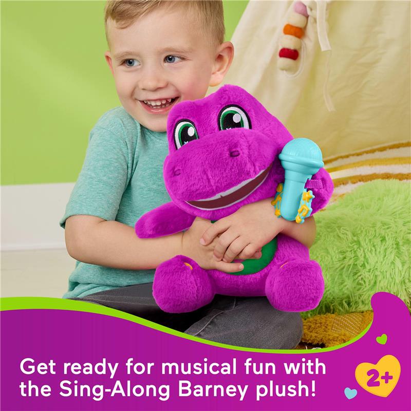 Child smiles while holding a purple Barney plush toy with a microphone, promoting musical play for toddlers.