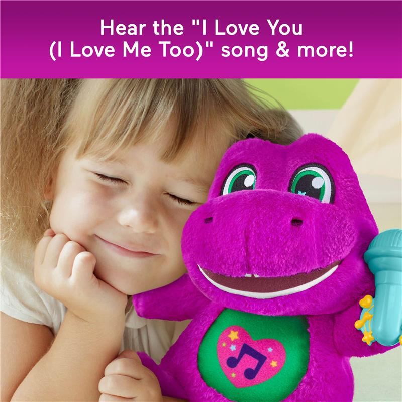 Toddler girl smiling while holding a purple Barney plush toy with a musical feature and a microphone accessory.