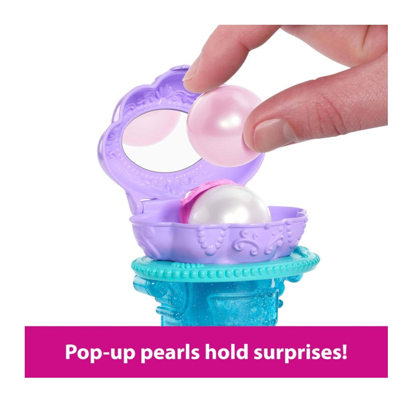 A hand lifts a pink pearl from a purple seashell playset with a mirror, part of the Fisher Price Disney Princess Ariel collection.