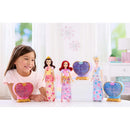 Young girl smiles while playing with Fisher Price Disney Princess dolls, featuring Belle, Ariel, and Cinderella, in a bright setting.