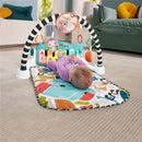 Fisher Price Glow & Grow Kick & Play Gym in blue, featuring a baby lying on a colorful mat with dangling toys and a mirror.