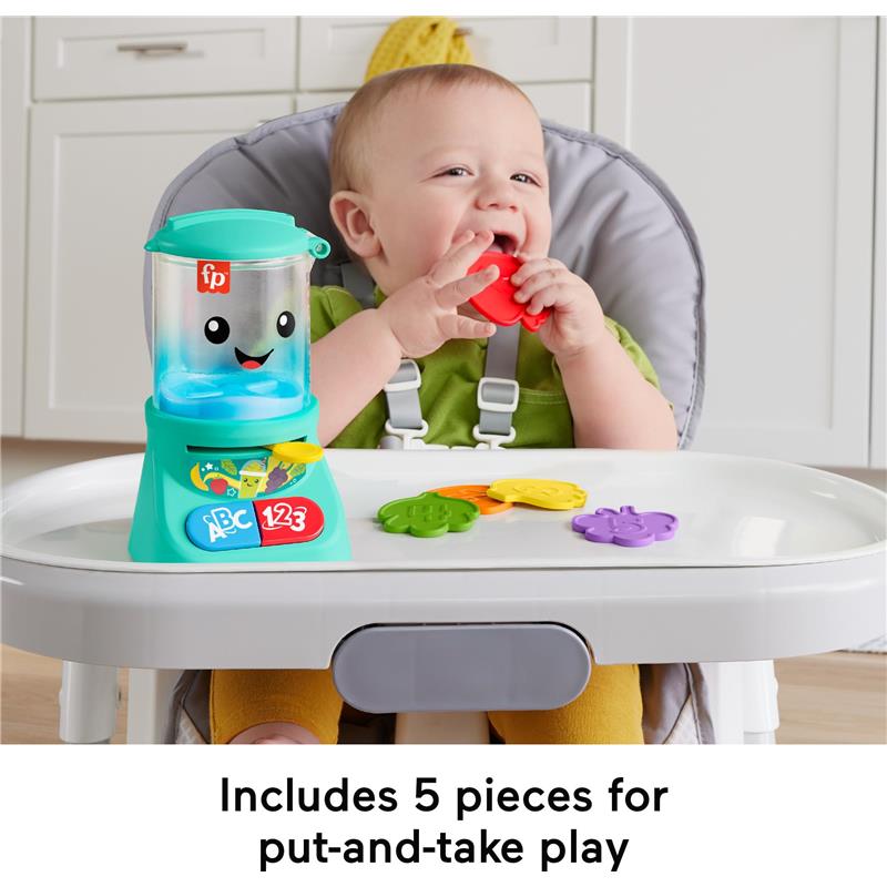 Toddler smiling while playing with the Fisher Price Laugh & Learn Smoothie Maker toy, holding a red shape, surrounded by colorful shapes on a tray.