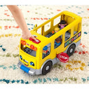 Yellow school bus toy with smiling face, buttons, and Little People figures inside, set on a colorful rug.