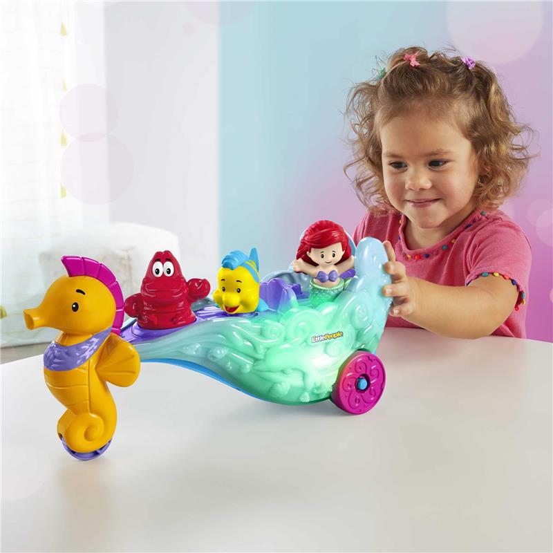 A child plays with a Fisher Price Little People toy featuring Disney Princess Ariel’s light-up sea carriage and aquatic characters.