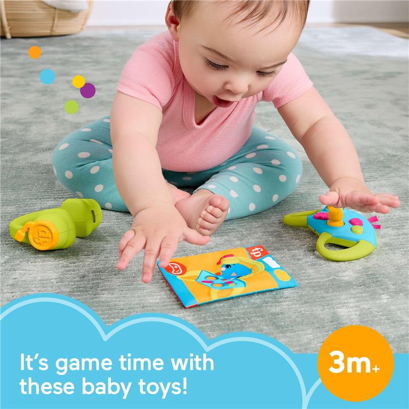 Newborn playing with Fisher Price Level-Up Little Gamer toys, including a green toy controller and a colorful activity card.