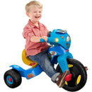 Child laughing while riding a blue Fisher Price Paw Patrol tricycle with lights and sounds features.