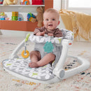 Portable baby chair featuring a smiling infant, geometric patterned seat pad, and colorful developmental toys.