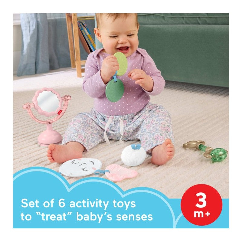 Infant sitting on a rug surrounded by colorful sensory toys, including a mirror and various textured objects, promoting sensory play.