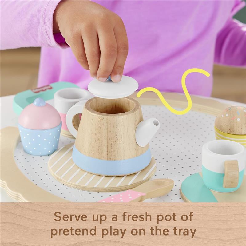 Wooden pretend play tea set featuring a teapot, cups, and a cupcake, with a child placing a lid on the teapot.