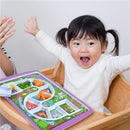 Child with pigtails excitedly raises arms in a high chair, beside the Fred & Friends Dinner Winner Forest Plate filled with food.