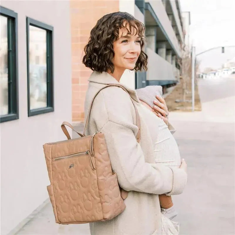 Minnie Mouse-themed Mini Minimal Backpack in light pink, worn by a woman holding a baby, outdoors.