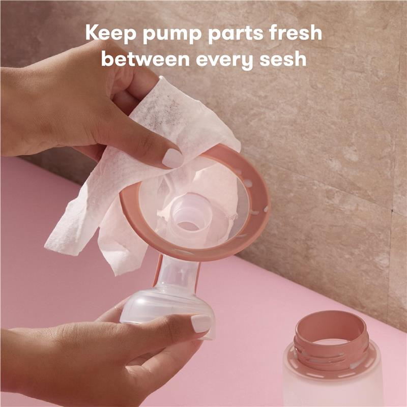 Breast pump parts being cleaned with a Frida Mom wipe, emphasizing hygiene during breastfeeding sessions.