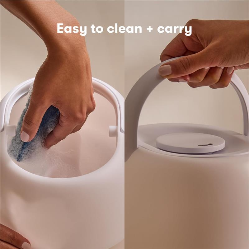 Hand cleaning the inside of a Fridababy 3-in-1 Cool Mist Humidifier, highlighting its easy-to-clean design and carrying handle.