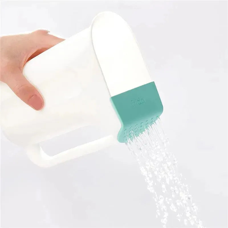 Fridababy Control The Flow Rinser being held, pouring water with a precision spout for easy rinsing.