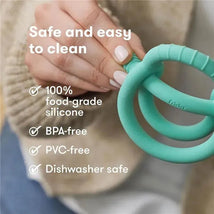 Vibrant teal FridaBaby Get-A-Grip Teether held in a hand, displaying features like 100% food-grade silicone, BPA-free, PVC-free, and dishwasher safe.