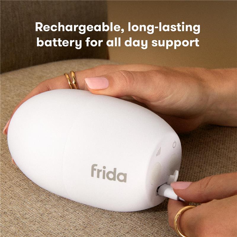 Portable hands-free rocker vibration device by Fridababy, being plugged in for charging, featuring a sleek white design.