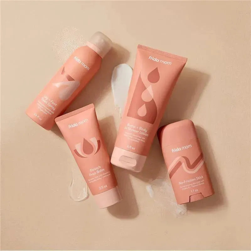 FridaMom Bump + Body In-Shower Lotion, 6 Oz, with three other products on a smooth surface, showcasing their pink packaging.