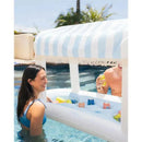 Floating cabana bar in blue and white, featuring drinks and two people enjoying refreshments in a pool.