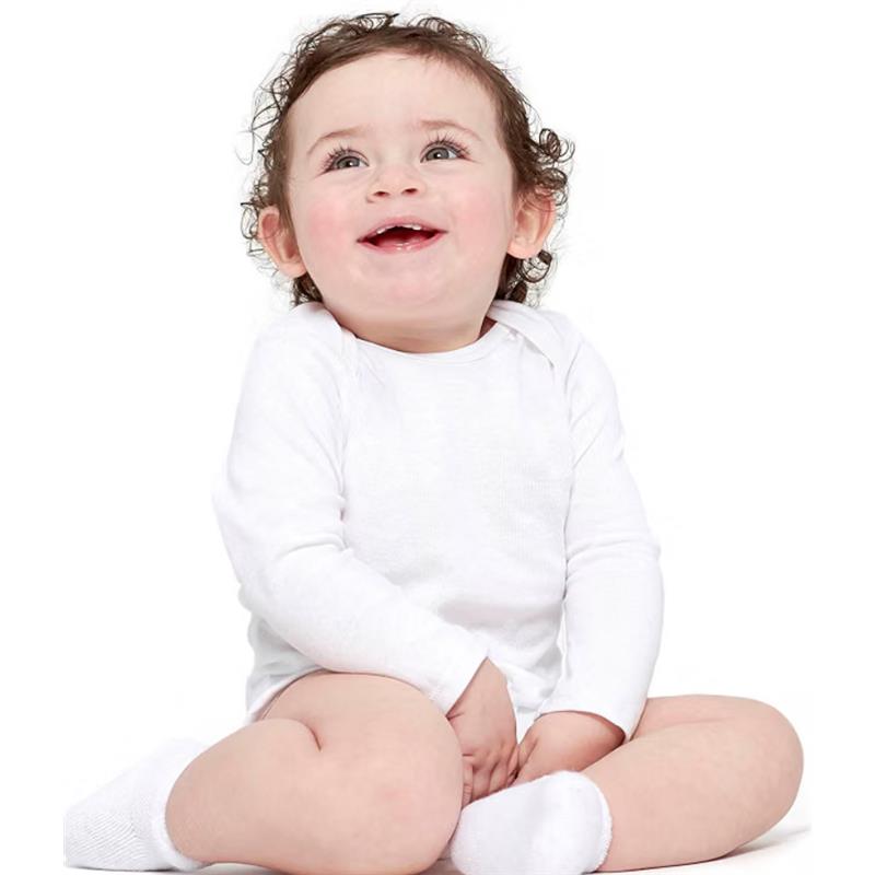 Baby smiling while seated, wearing a white long-sleeve onesie with mitten-cuffs.