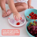 Kids are using the GoBe Snack Spinner to sort cherry tomatoes, with bowls of grapes and tomatoes visible.