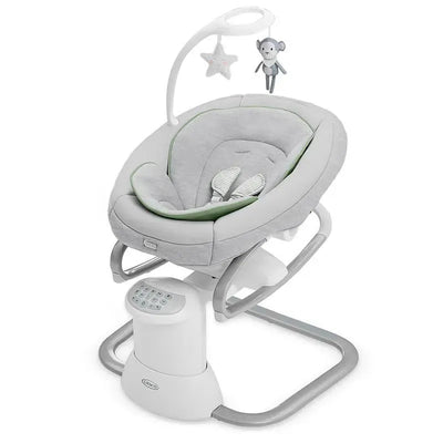 Graco Soothe My Way baby swing with a removable rocker, featuring a gray and green seat, electronic controls, and hanging toys.