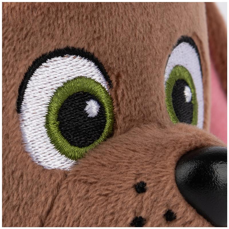Close-up of plush toy Zuma from PAW Patrol, featuring large green and black eyes, brown fur, and a friendly expression.