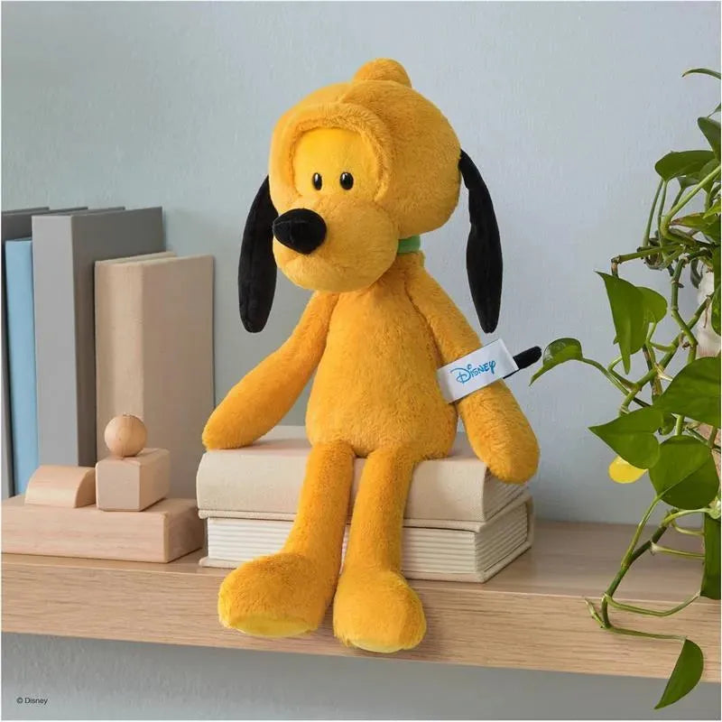 Gund - Pluto 15 plush toy, featuring a yellow dog with black ears, sitting on a shelf next to wooden blocks and plants.