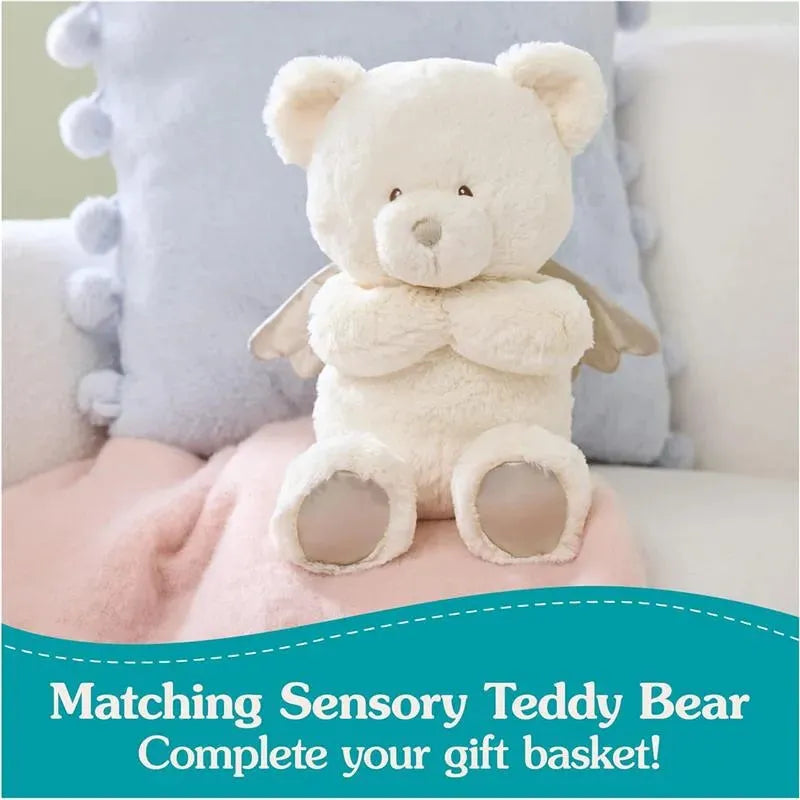 Spiritual Bear Lovey by Gund, a soft, cream-colored teddy bear with angel wings, sits on a pastel blanket, promoting gift ideas.