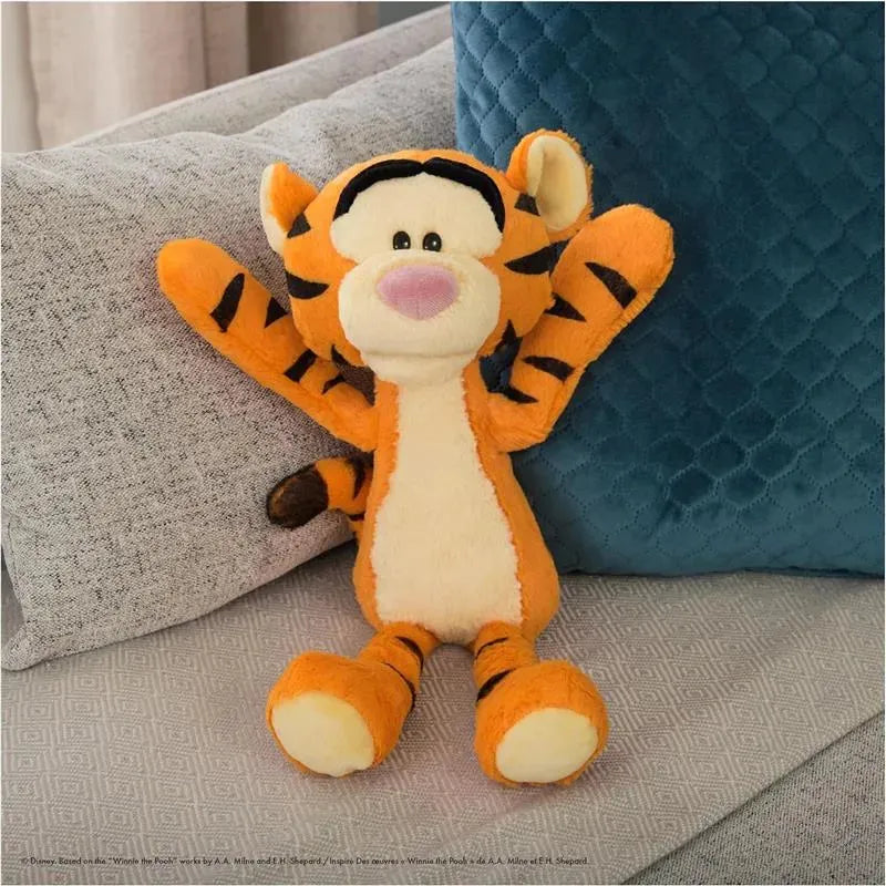 Tigger plush toy with orange fur, black stripes, and a cheerful expression, seated on a light gray couch.