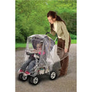 Weather shield for stroller, protecting two children inside as a woman adjusts the cover outdoors.