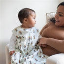 Baby wearing a HALO SleepSack wearable blanket with Mickey Mouse design, sitting with a smiling adult.