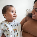 Infant wearing a HALO SleepSack Wearable Blanket featuring Mickey Mouse print, smiling at a woman holding them.