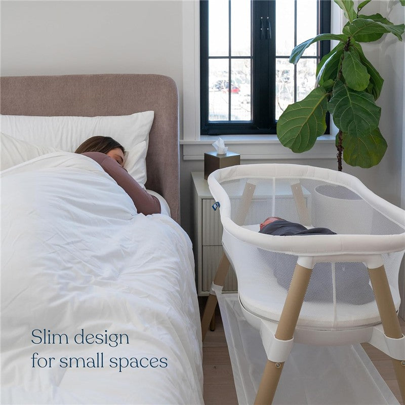Baby in HALO BassiNest Essential Sleeper beside a sleeping woman, showcasing its slim design for small spaces.