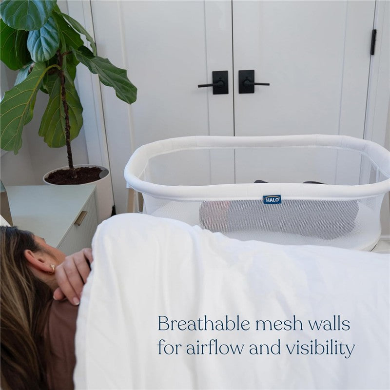 HALO BassiNest Essential Sleeper in white with mesh walls, designed for airflow and visibility next to a sleeping person.