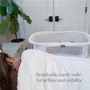 HALO BassiNest Essential Sleeper in white with mesh walls, designed for airflow and visibility next to a sleeping person.