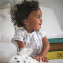 Child smiling while wearing a Harry Potter-themed SleepSack, sitting with a plush toy on a bed.