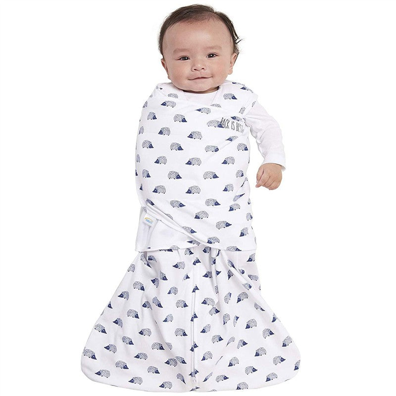 HALO SleepSack Swaddle in navy with hedgehog pattern, featuring a smiling baby wrapped securely, promoting safe sleep.