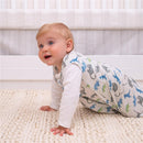 Baby crawling on a textured rug, wearing a HALO SleepSack blanket in a watercolor dinosaur pattern.