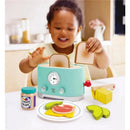A young child joyfully interacts with the Hape Ding & Pop-Up Toaster, placing wooden toast slices into it surrounded by play food.